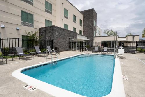 a swimming pool with chairs and a building at Fairfield Inn & Suites Arkadelphia in Arkadelphia