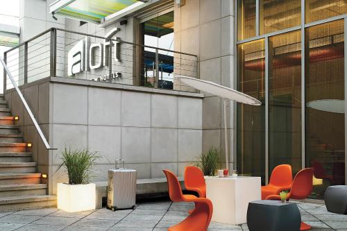 a lobby of a building with orange chairs and tables at Aloft Harlem in New York
