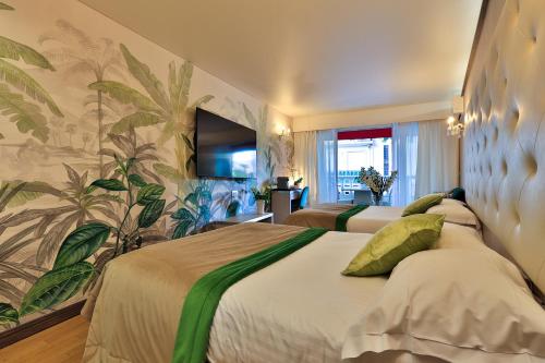 カンヌにあるHotel Le Fouquet'sのベッド2台とテレビが備わるホテルルームです。
