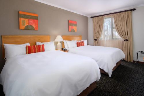 a hotel room with two beds and a window at Protea Hotel by Marriott Polokwane Landmark in Polokwane
