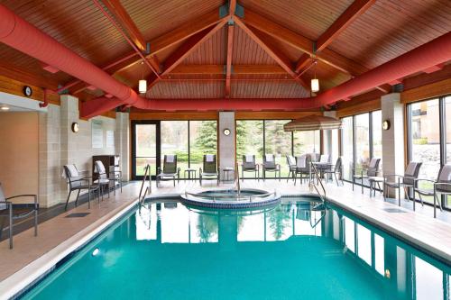 uma piscina com cadeiras e mesas num edifício em Fairfield Inn by Marriott Rochester East em Webster