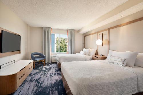 a hotel room with two beds and a flat screen tv at Fairfield Inn & Suites by Marriott Reno Sparks in Sparks