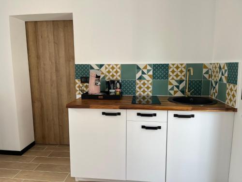 a kitchen with white cabinets and a sink at Logement de charme - W&B House in Dorlisheim