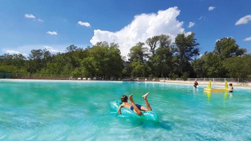 a woman laying on an inner tube in a swimming pool at Camping Tikayan La Célestine in Beynes