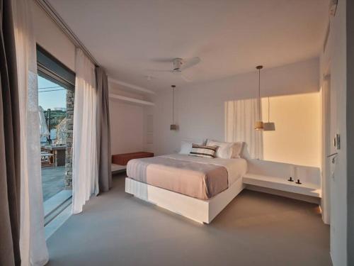 a white bedroom with a bed and a balcony at Olithos Villas in Krotiri