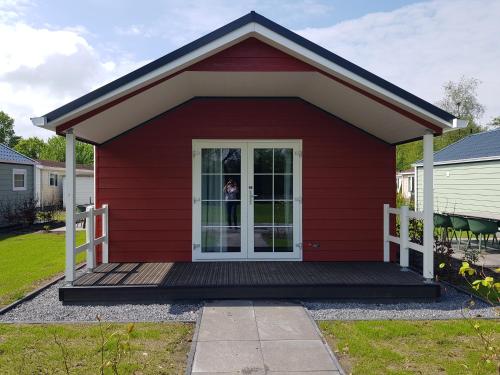 a red house with a porch and a door at De Bijsselse Enk, Noors chalet 16 in Nunspeet