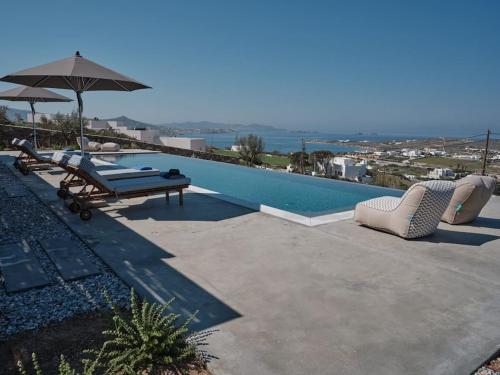 a swimming pool with two lounge chairs and an umbrella at Olithos Villas in Krotiri