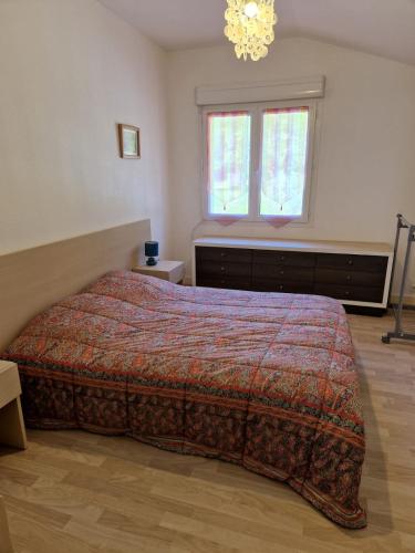 une chambre avec un lit, une fenêtre et un lustre dans l'établissement Gîte Pauline, à Saint-Martial-de-Valette