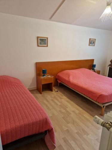Cette chambre comprend 2 lits avec des draps rouges et du parquet. dans l'établissement Gîte Pauline, à Saint-Martial-de-Valette