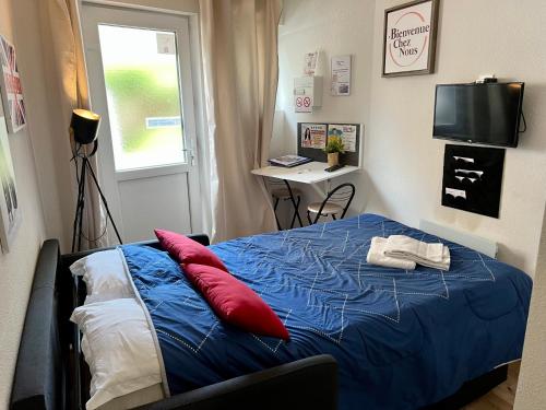 - une chambre avec un lit bleu et des oreillers rouges dans l'établissement STUDIO Av MARX DORMOY CLERMONT CENTRE B, à Clermont-Ferrand