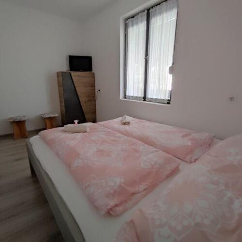 ein Schlafzimmer mit einem rosa Bett und einem Fenster in der Unterkunft Horizont Apartman Szihalom in Szihalom