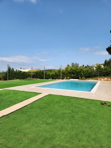 a swimming pool with green grass next to it at Luxe Villa Amfiario in Attica region, pool & breathtaking views! in Kalamos