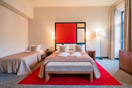 a hotel room with two beds and a red wall at VICTORIA Hotel Kaunas in Kaunas