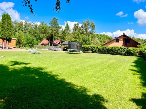 a large lawn with a house in the background at Domek letniskowy Sport&Relax in Kopalino
