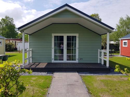 a green house with a porch and a door at De Bijsselse Enk, Noors chalet 17 in Nunspeet