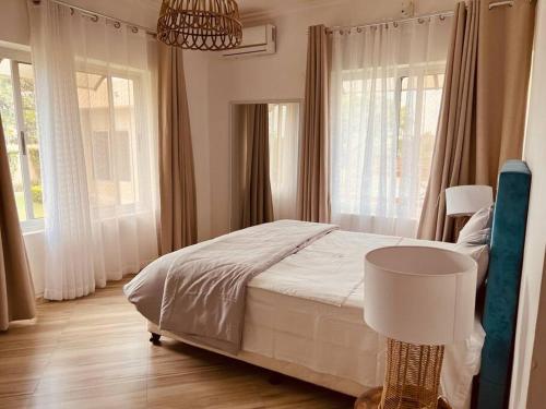 a bedroom with a bed and windows and a lamp at Casa Conforto Bilene in Vila Praia Do Bilene