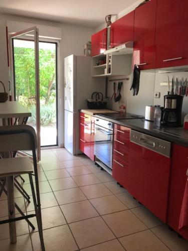 - une cuisine avec des placards rouges et une table dans l'établissement T3, jardin privatif, 2 chambres, Côte Basque (Anglet), à Anglet