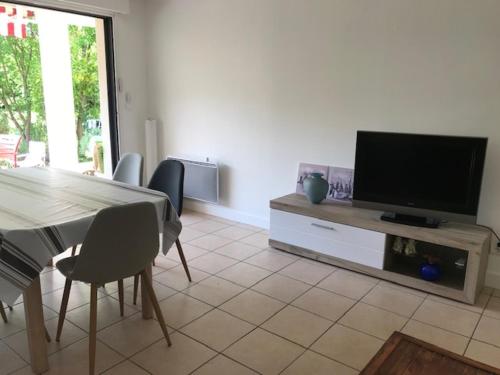 Il comprend un salon doté d'une table et d'une télévision à écran plat. dans l'établissement T3, jardin privatif, 2 chambres, Côte Basque (Anglet), à Anglet