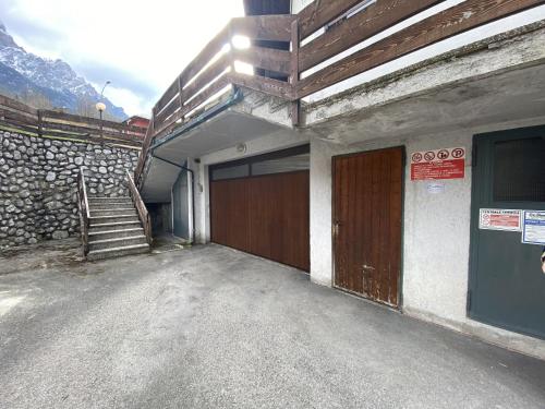 a building with a garage with a door and stairs at Casa Marmarole in Borca di Cadore