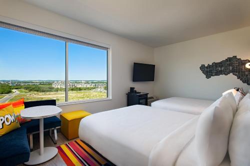 a hotel room with two beds and a large window at Aloft San Antonio UTSA Area in San Antonio