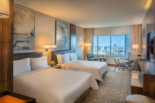 a hotel room with two beds and a desk at JW Marriott Hotel Santo Domingo in Santo Domingo