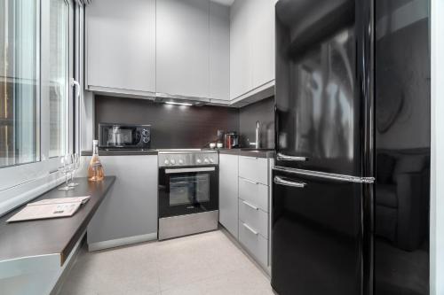 a kitchen with a black refrigerator and white cabinets at Utopia Eco Retreat in Skiathos Town