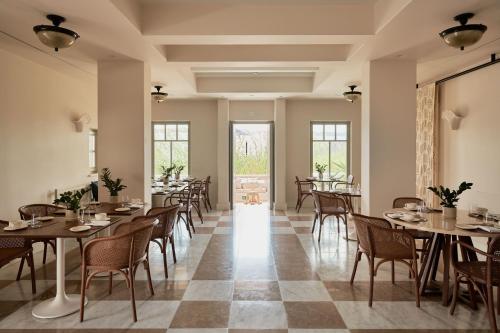 Un comedor con mesas y sillas y ventanas. en Cosme, a Luxury Collection Resort, Paros, en Naousa