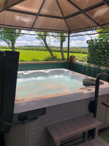 a jacuzzi tub with an umbrella in a yard at Peaceful Holiday Lodge with Hot Tub in Lincolnshire