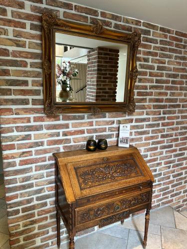 a mirror on a brick wall with a wooden table at Hotel Grand Canal in Delft