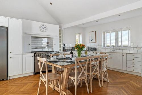 a kitchen with a large wooden table and chairs at Luxury House, SeaViews, En-Suites & Private Pool in Saundersfoot