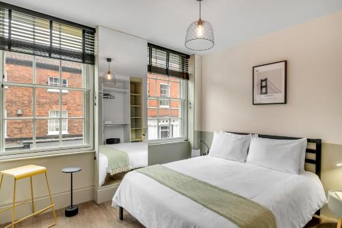 a bedroom with a bed and two windows at Nadler Studios in Norwich