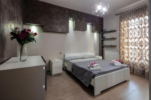 1 dormitorio con 1 cama y un jarrón de flores en Galì Holidays Casa Vacanze, en Acquedolci