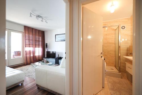 a living room with a white couch and a bathroom at Apartman Cruiser in Zadar