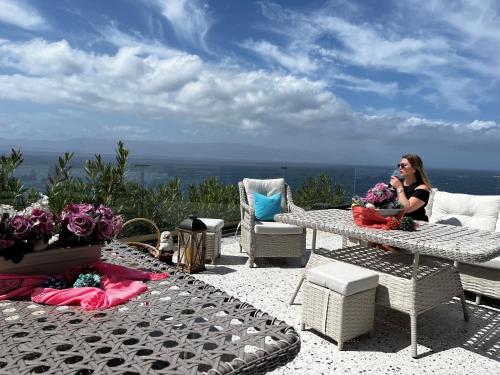 Eine Frau, die an einem Tisch auf einer Terrasse sitzt in der Unterkunft Mavi Panorama Villa in Cesme