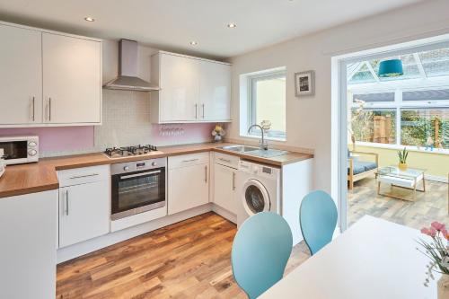uma cozinha com armários brancos e uma mesa e cadeiras em Host & Stay - Garden Cottage em Durham