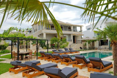 a villa with a swimming pool with lounge chairs and a house at Casa Del Mar in Ksamil
