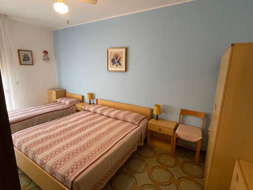 a room with two beds and a chair in it at Condominio Simma in Bibione