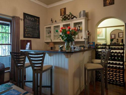a bar with chairs and a vase of flowers at Harfield Guest Villa in Cape Town