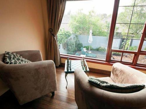 a living room with two chairs and a table and a window at Harfield Guest Villa in Cape Town