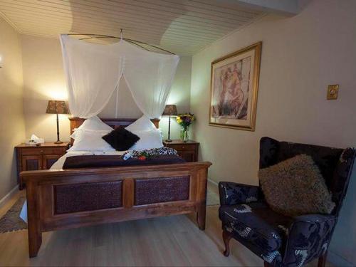a bedroom with a bed with a canopy and a chair at Harfield Guest Villa in Cape Town