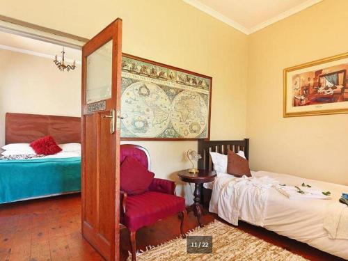 a bedroom with a bed and a chair and a mirror at Harfield Guest Villa in Cape Town