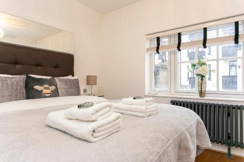 um quarto com uma cama com toalhas brancas em Hidden gem in Covent Garden em Londres