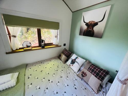 a bedroom with a bed with a bull picture on the wall at Romantic Shepherd Hut with Optional Hot Tub in Snowdonia in Dolgellau