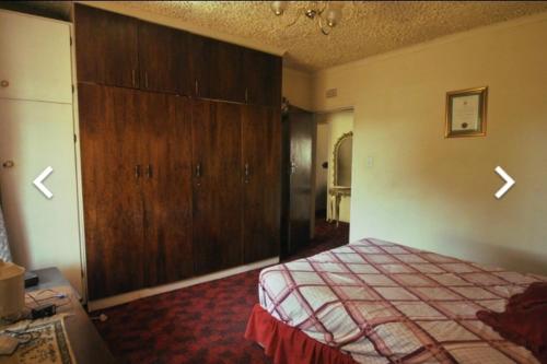 a bedroom with a bed and a large wooden cabinet at House of creations in Diepkloof