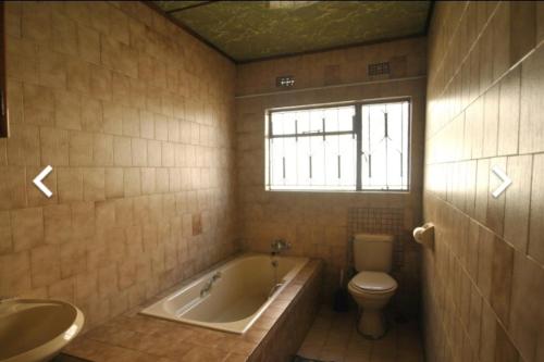 a bathroom with a tub and a toilet and a sink at House of creations in Diepkloof