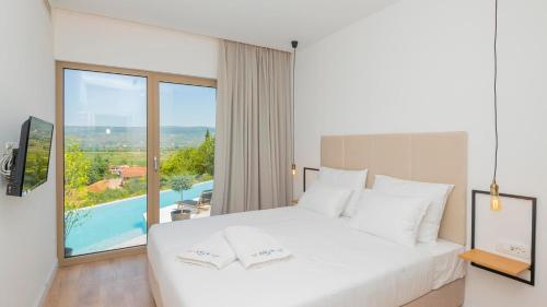 1 dormitorio con cama blanca y ventana grande en Modern and luxurious villa with swimming pool in Zmijavci, en Zmijavci