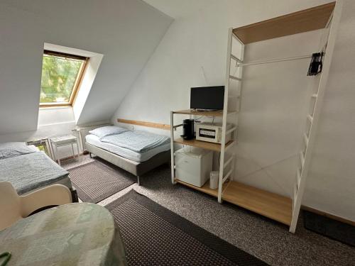 um pequeno quarto com uma cama e uma televisão em Bigus em Berlim
