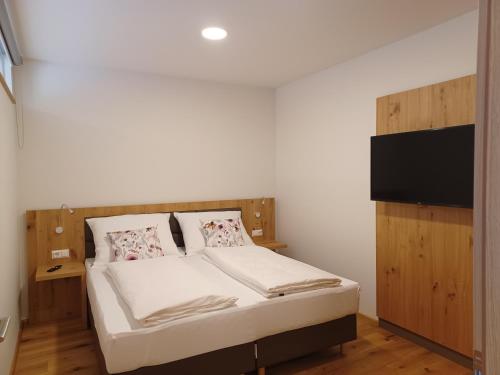 a small bedroom with a bed and a tv at Weingut Königshofer in Neusiedl am See