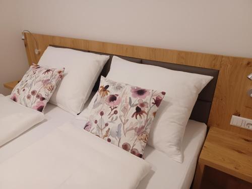 a bed with white sheets and pillows with flowers at Weingut Königshofer in Neusiedl am See