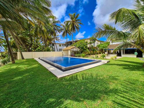 a swimming pool in a yard with palm trees at Star Beach Guest House in Negombo